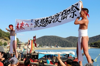 ふんどし姿の男衆が担いだ「バタ板」の上で、船祭りの発展を願って横断幕を披露した氏子たち＝１１日午後、赤穂市坂越（撮影・桑名良典）