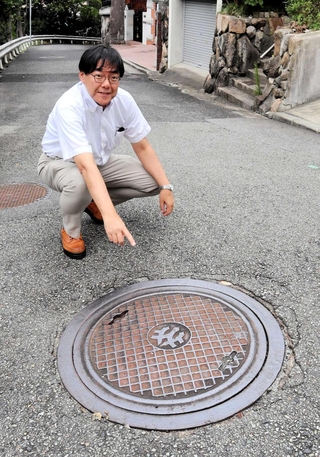 御影町章のマンホールのふたについて解説する道谷卓さん＝神戸市東灘区御影山手５