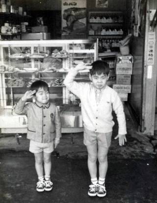 建て替え前の店頭で兄と一緒にポーズを取る山口仁さん（左）＝１９７０年ごろ（提供）