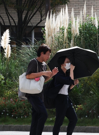 西洋ススキの穂が輝く街角では、日傘や半袖姿の通行人の姿が見られた＝２１日午後、神戸市中央区浪花町（撮影・辰巳直之）