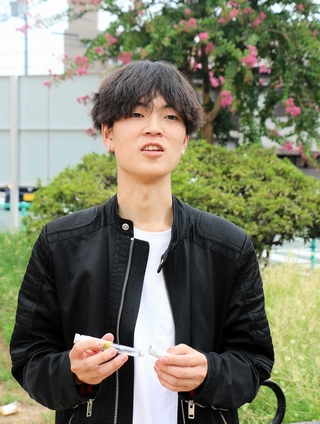 自宅で認知症の祖母を介護する大学生石川達也さん。手に持つのは、祖母のおなかに打つインスリン注射器＝姫路市内