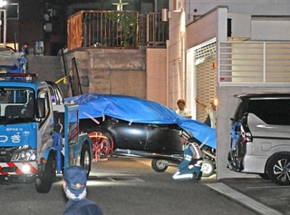 シャッターを破って民家の車庫に突っ込み、レッカー車で運び出される車＝９月３０日夜、神戸市兵庫区荒田町３