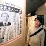 ノーベル化学賞受賞を伝える号外を見る人たち＝７日夜、デュオ神戸（撮影・丸山桃奈）
