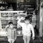 建て替え前の店頭で兄と一緒にポーズを取る山口仁さん（左）＝１９７０年ごろ（提供）