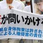 少女の写真とともに神戸地裁に入る母親（左）＝２１日午前、神戸市中央区橘通２