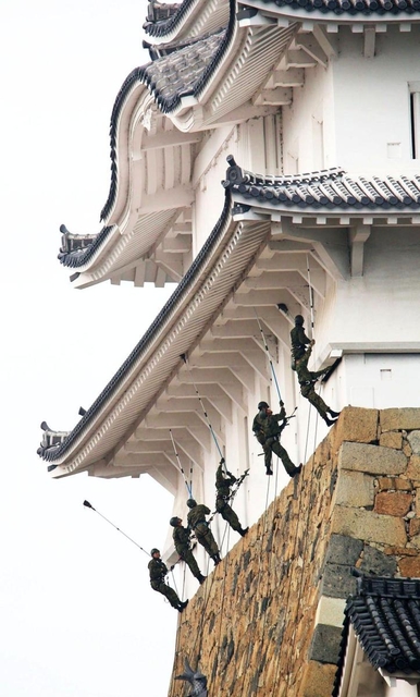 石垣を上って姫路城大天守のすす払いをする陸自のレンジャー隊員ら＝１８日午前、姫路市本町（撮影・小林良多）