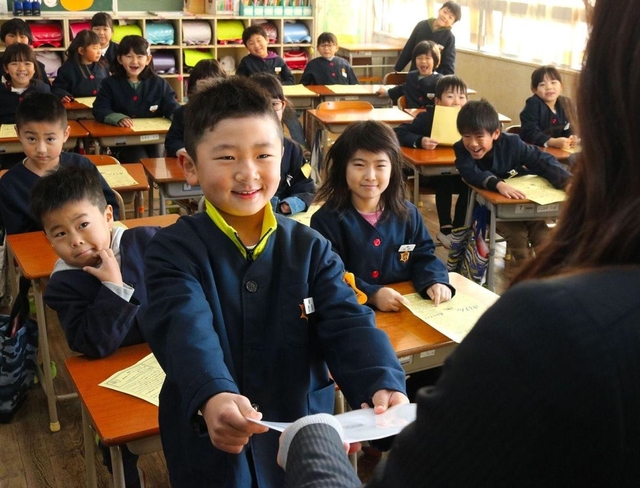 笑顔で通知表を受け取る児童＝２３日午前、兵庫県播磨町北本荘４