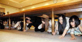 第１回のシェイクアウト訓練で、机の下に潜り込むＡＫＢ４８のメンバーと久元喜造神戸市長（右から４人目）＝２０１５年１月１５日、神戸市中央区加納町６、神戸市役所