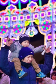 色鮮やかな光の中を肩車して歩く親子＝６日夜、神戸市中央区加納町６（撮影・秋山亮太）