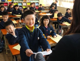 笑顔で通知表を受け取る児童＝２３日午前、兵庫県播磨町北本荘４