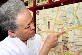 湊川神社の最寄り駅、市営地下鉄大倉山駅を示す権宮司の西原秀樹さん＝神戸市中央区多聞通３