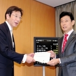 西村康稔担当相（右）に共同宣言を手渡した久元喜造神戸市長＝１９日午後、東京都千代田区
