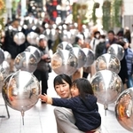 宙に浮かぶ鏡面風船を眺めながらアーケードを行き交う人たち＝２０日午後、神戸市中央区三宮町２、三宮本通商店街（撮影・秋山亮太）