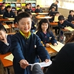 笑顔で通知表を受け取る児童＝２３日午前、兵庫県播磨町北本荘４