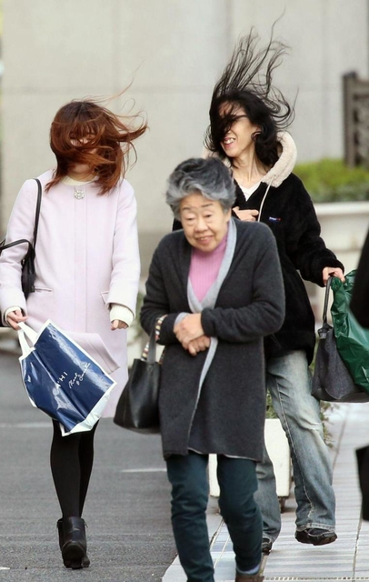 強風にあおられ髪を乱しながら歩く女性ら＝８日午後、神戸市中央区のＪＲ神戸駅前（撮影・辰巳直之）