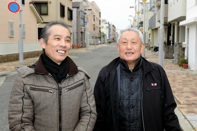 震災の火災で亡くなった林譲弥さんの救助活動以来、２５年ぶりに再会した長男幸弘さん（左）と菅利秋さん＝１７日午前８時２５分、神戸市長田区日吉町５（撮影・後藤亮平）