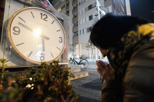 地震発生時刻で停止した時計のモニュメントに手を合わせる女性＝１７日午前６時３分、西宮市田中町（撮影・三津山朋彦）西宮中央商店街