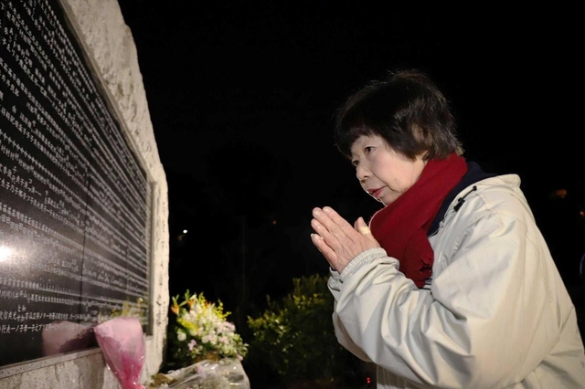 両親の名前が刻まれた碑の前で、手を合わせる原田美智子さん＝１７日午前６時３１分、西宮市奥畑（撮影・吉田敦史）