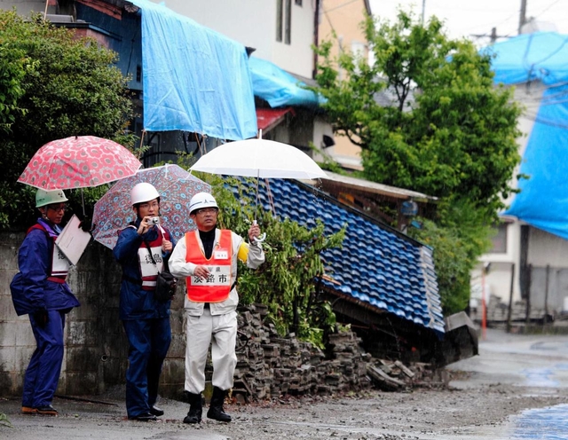 熊本地震の被災地で、派遣職員として家屋被害認定調査に当たる淡路市の職員（右）＝２０１６年５月、熊本県益城町