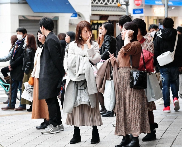 記録的な暖かさの中、思わずコートや上着を腕に掛けて過ごす人たち＝２８日午後、神戸市中央区（撮影・秋山亮太）