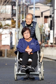 夫の雅男さんに押してもらいながら、車いすで近所を散歩する村田延子さん＝神戸市北区鹿の子台（撮影・風斗雅博）