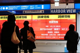 訓練用の地震情報が映し出されたデジタルサイネージ（電子看板）を見つめる人たち＝１７日午前９時６分、神戸市中央区東川崎町１（撮影・大山伸一郎）