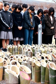 竹灯籠を前に、東日本大震災で亡くなった人たちに黙とうをささげる高玉そらさん（左手前）＝１７日午後２時４６分、神戸市中央区脇浜海岸通１