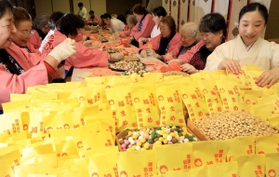 福を呼ぶ豆を袋に詰めていくみこたち＝２２日午後、湊川神社