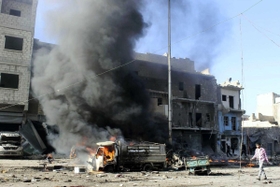 政府軍によるとされる空爆を受け煙を上げる車＝２０１３年、シリア・アレッポ