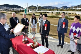 表彰式で高梨柳太郎社長（左）から賞状を受け取る青山裕一さん（中央）＝姫路競馬場