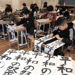 書き初めで元気よく筆を走らせる児童たち＝７日午前、神戸市立兵庫大開小