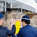 特定抗争指定暴力団に指定された山口組の総本部に標章を貼る捜査員ら＝７日午前、神戸市灘区篠原本町４