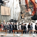 解体が進む街で通勤を急ぐサラリーマンら。スーツにマスク姿も目立つ＝１９９５年４月１８日、神戸市中央区・元町