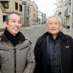 震災の火災で亡くなった林譲弥さんの救助活動以来、２５年ぶりに再会した長男幸弘さん（左）と菅利秋さん＝１７日午前８時２５分、神戸市長田区日吉町５（撮影・後藤亮平）