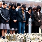 竹灯籠を前に、東日本大震災で亡くなった人たちに黙とうをささげる高玉そらさん（左手前）＝１７日午後２時４６分、神戸市中央区脇浜海岸通１