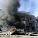 政府軍によるとされる空爆を受け煙を上げる車＝２０１３年、シリア・アレッポ