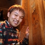 店内の柱に初めて書いた自身のサインとともに笑顔を見せる松永貴志さん＝２９日夜、芦屋市東山町（撮影・風斗雅博）