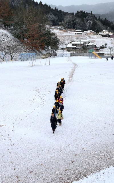 今シーズン初めて平野部で積雪を観測した宍粟市波賀町。白くなった校庭を児童が登校した＝６日午前、波賀小学校（撮影・小林良多）