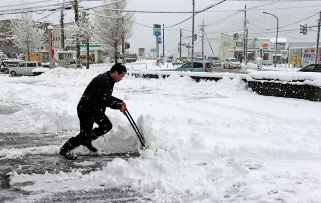 市街地でもまとまった積雪を記録。銀行の駐車場で行員が雪かきに追われた＝６日午前８時すぎ、養父市八鹿町八鹿（撮影・桑名良典）