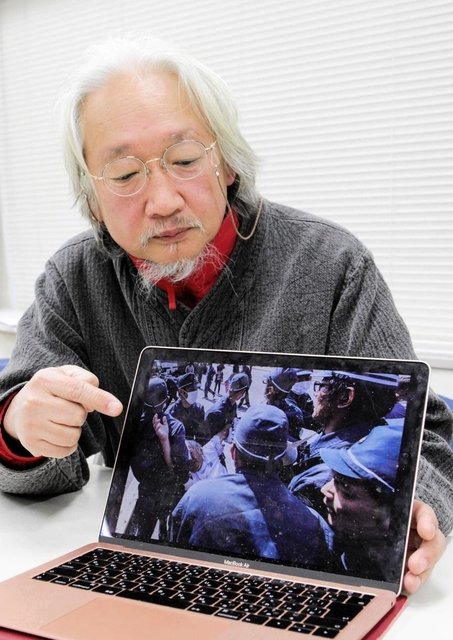 沖縄県警の機動隊員らに取り囲まれた際の写真を示すこかんほさん＝２５日、神戸市中央区橘通２、神戸司法記者クラブ