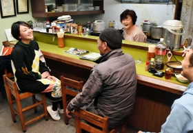 東京から移住し、なじみになった近所の居酒屋で常連客と話す青年団の渡辺瑞帆さん（左）。「まちも演劇も楽しめるにはどうしたらいいか模索中」＝豊岡市日高町日置