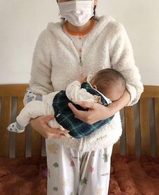 小さな長男を抱く女性。ほとんど外出していないという＝５日、中国湖北省武漢市（女性提供）