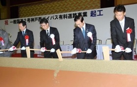 工事の安全と早期開通を願い、くわ入れを行う関係者ら＝１６日午後、神戸市西区平野町宮前