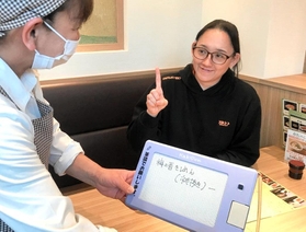 明石市の公的助成を利用した筆談ボードで注文する涌井由賀里さん（右）＝明石市大明石町１
