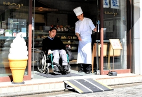 車いすで簡易スロープを利用する飯塚理能さん＝明石市本町１
