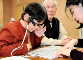 眼鏡に取り付けた視覚支援機器で、新聞の読み取りを体験する参加者＝丹波篠山市、丹南健康福祉センター