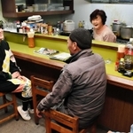 東京から移住し、なじみになった近所の居酒屋で常連客と話す青年団の渡辺瑞帆さん（左）。「まちも演劇も楽しめるにはどうしたらいいか模索中」＝豊岡市日高町日置