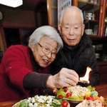 北朝鮮に拉致された有本恵子さんの５７歳の誕生日を祝うケーキに火をともす、有本明弘さん（右）、嘉代子さん夫妻＝２０１７年１月１２日、神戸市長田区