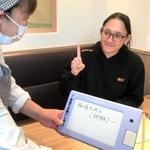 明石市の公的助成を利用した筆談ボードで注文する涌井由賀里さん（右）＝明石市大明石町１