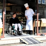 車いすで簡易スロープを利用する飯塚理能さん＝明石市本町１